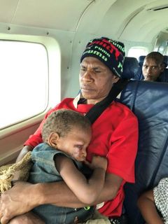 Aube Kumaruma med sin skadde sønn på MAFs fly.