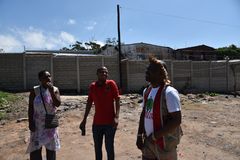 Thapelo Mohapi (midten) og S´bu Zikode (t.h.) utenfor en bosetting i Durban. Landeieren har satt opp mur for å hindre Det er ikke satt inn rømningsveier og brannfaren er stor. Foto: Torunn Aaslund/Norsk Folkehjelp