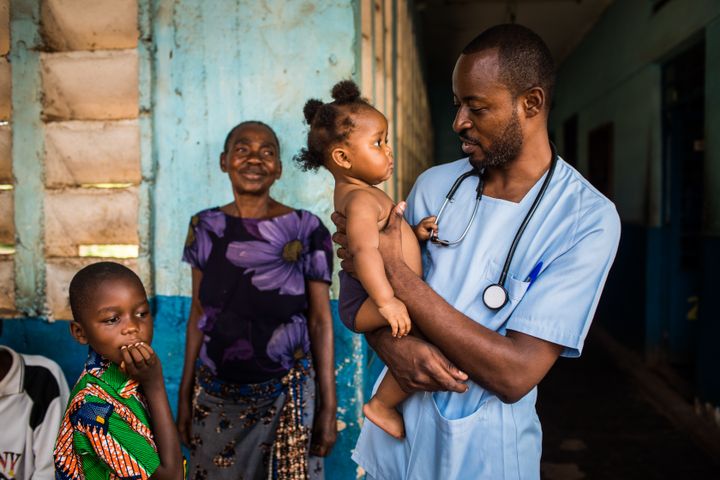 Doktor Elvis Badianga Kumbu holder en liten jente i armene etter at hun var inne for behandling på barnesykehuset i Mbuji-Mayi i Kongo. Foto: UNICEF / Vincent Tremeau