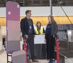 Aslak Sverdrup, lufthavndirektør for Bergen lufthavn og Ellen Marie Risbruna, arrangør av Bergen strikkefestival er fornøyd med strikkearbeidet. Trine Ø. Hauge fra Aviator gleder seg til å ta i mot passasjerer på innsjekk.