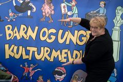 Kulturminister Trine Skei Grande viser hvor stor barn og unges kulturmelding vil bli. Foto: Knut Sørhusbakken