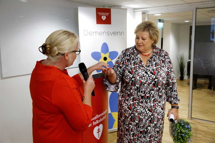 Generalsekretær i Nasjonalforeningen for folkehelsen, Lisbet Rugtvedt, overrekker Statsministeren en forglemmegei-pin, som markerer at hun har blitt Norges første Demensvenn. foto: Paal Audestad
