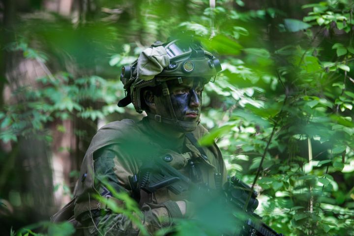soldat med kamuflasje i tett skog