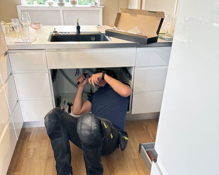 Rørlegger som arbeider under kjøkkenvask