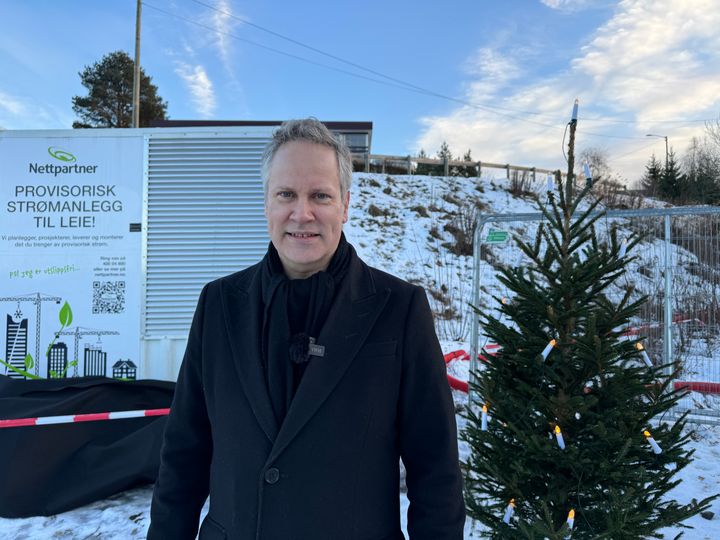 Samferdselsminister Jon-Ivar Nygård står foran en nettstasjon og julegran på anleggsplass.