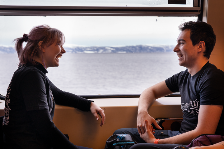to ungdommer sitter og smiler ved vindu på tog